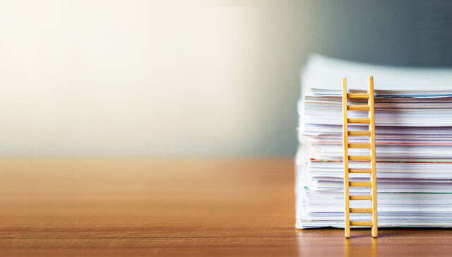 Stack of documents with small wooden ladder on desk, career growth, bureaucracy pressure, corporate ladder, office life, paperwork overload, productivity stress, administrative burden